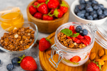 Bowl of granola with yogurt and fresh berries on a texture table. Yogurt berries, acai bowl, spirulina bowl. Healthy food, balanced breakfast. Strawberries, blueberries, kiwi, peach, almonds and chia.