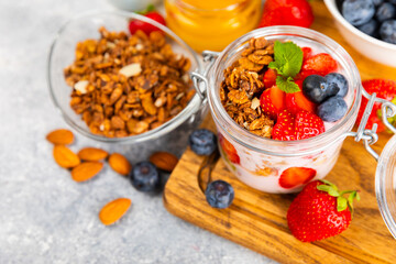 Bowl of granola with yogurt and fresh berries on a texture table. Yogurt berries, acai bowl, spirulina bowl. Healthy food, balanced breakfast. Strawberries, blueberries, kiwi, peach, almonds and chia.