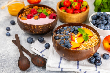 Bowl of granola with yogurt and fresh berries on a texture table. Yogurt berries, acai bowl, spirulina bowl. Healthy food, balanced breakfast. Strawberries, blueberries, kiwi, peach, almonds and chia.