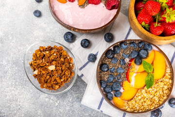 Bowl of granola with yogurt and fresh berries on a texture table. Yogurt berries, acai bowl, spirulina bowl. Healthy food, balanced breakfast. Strawberries, blueberries, kiwi, peach, almonds and chia.