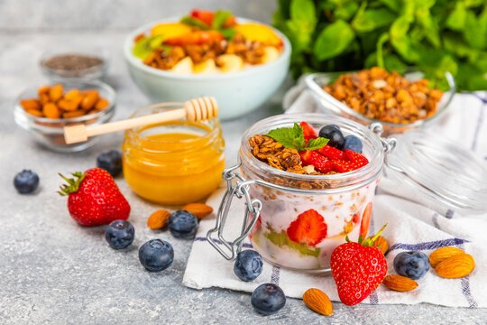 Bowl of granola with yogurt and fresh berries on a texture table. Yogurt berries, acai bowl, spirulina bowl. Healthy food, balanced breakfast. Strawberries, blueberries, kiwi, peach, almonds and chia.