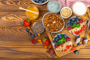 Bowl of granola with yogurt and fresh berries on a texture table. Yogurt berries, acai bowl, spirulina bowl. Healthy food, balanced breakfast. Strawberries, blueberries, kiwi, peach, almonds and chia.
