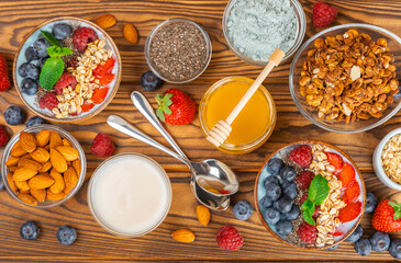 Obraz na płótnie Canvas Bowl of granola with yogurt and fresh berries on a texture table. Yogurt berries, acai bowl, spirulina bowl. Healthy food, balanced breakfast. Strawberries, blueberries, kiwi, peach, almonds and chia.
