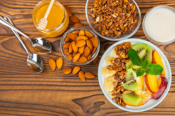 Bowl of granola with yogurt and fresh berries on a texture table. Yogurt berries, acai bowl, spirulina bowl. Healthy food, balanced breakfast. Strawberries, blueberries, kiwi, peach, almonds and chia.