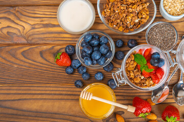 Bowl of granola with yogurt and fresh berries on a texture table. Yogurt berries, acai bowl, spirulina bowl. Healthy food, balanced breakfast. Strawberries, blueberries, kiwi, peach, almonds and chia.