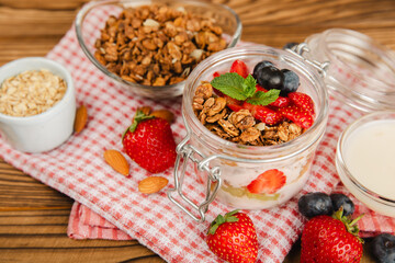 Bowl of granola with yogurt and fresh berries on a texture table. Yogurt berries, acai bowl, spirulina bowl. Healthy food, balanced breakfast. Strawberries, blueberries, kiwi, peach, almonds and chia.