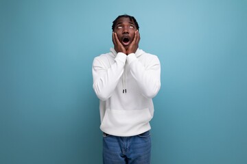 surprised african young brunette man in white sweater with open mouth