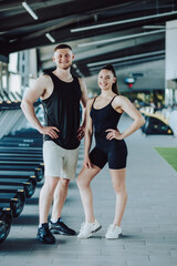 Fototapeta na wymiar Fitness enthusiasts Portrait of a man and woman in the gym, confident gazes at the camera. Fitness Partners Dynamic Gym Portrait of a Young Man and Woman