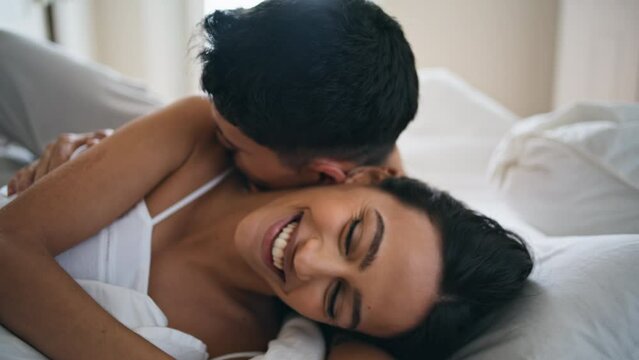 Enamoured couple bonding under blanket close up. Tender groom kissing woman