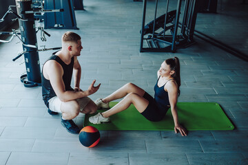 a personal trainer is seen having an informative conversation with a female client at the gym,...