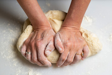 Unrecognizable woman kneading dough. Dough for dumplings, dumplings, pies.