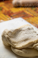 Piece of kneaded bread dough on cutting board in kitchen.