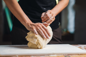 Cooking dough. Women's hands kneading dough in kitchen. Unrecognizable woman is engaged in cooking.