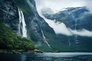 View from the sea to the mountains with a waterfall in the fog. - obrazy, fototapety, plakaty