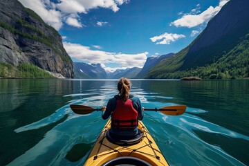 View from the back of a girl in a canoe floating on the water among the fjords. - obrazy, fototapety, plakaty