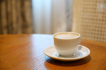 Hot Coffee in white cup on wooden table in kitchen room at comfort home.
