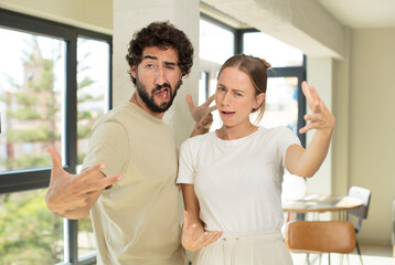 young adult couple looking happy, arrogant, proud and self satisfied, feeling like a number one