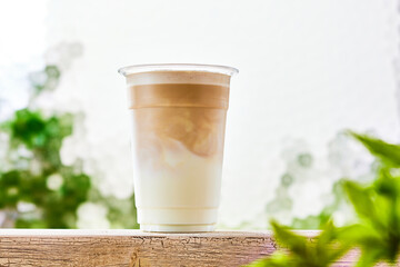 カフェラテ、プラスチックコップに入ったミルクにコーヒーを注ぐ-Iced Latte with Layered Coffee and Milk