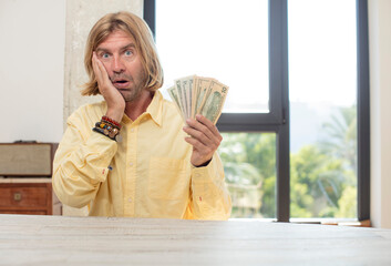 young adult caucasian man feeling extremely shocked and surprised. dollar banknotes concept