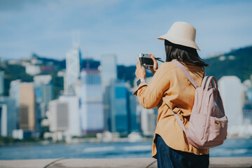 Asian tourist, cute woman with long hair are traveling in Hong Kong along with map and her camera with fun on her holiday,traveler relaxing and enjoying at city and building in Hong Kong.