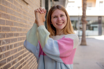 pretty young woman feeling happy, surprised and proud, shouting and celebrating success with a big smile