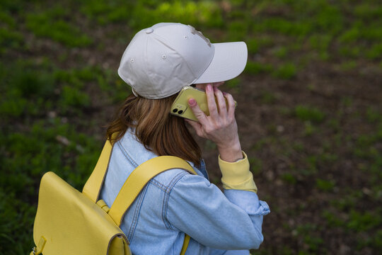 woman is talking on the phone against the background of grass