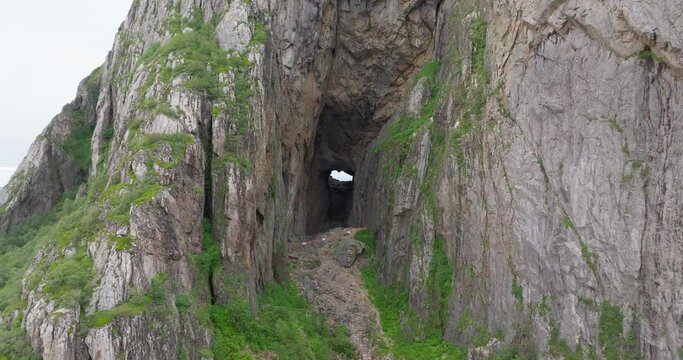 Dark eroded hole cave through Torghatten mountain; drone down crane motion