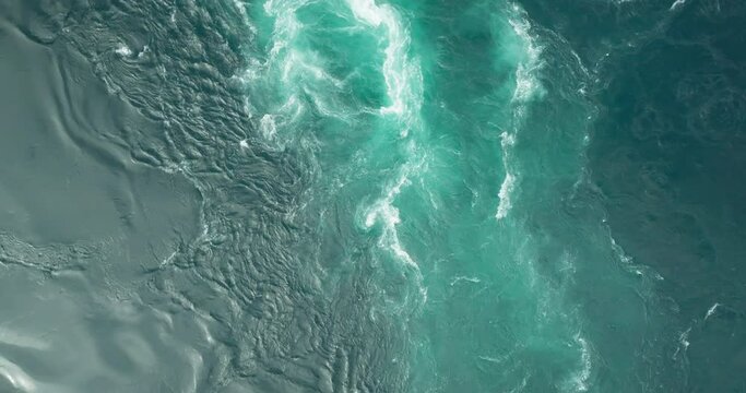 Flowing currents in azure blue Saltstraumen maelstrom with whirlpools; drone