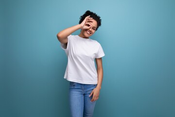 surprised young brunette woman with afro hair in a white t-shirt uses her hands for gesticulation and communication