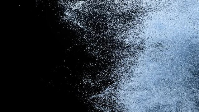 Abstract concept. Colored powder scatters on a black isolated background. Sand. Spray. Blue color. Slow motion.