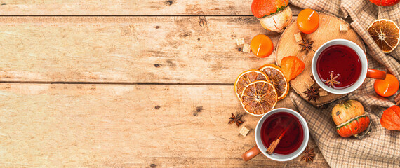 Fototapeta na wymiar Spicy hot tea. Autumn good mood, traditional fall beverage in cups. Pumpkin, scarf, candles