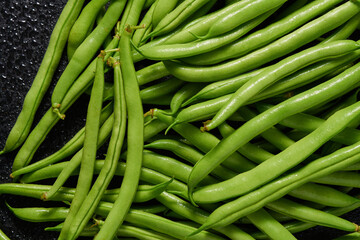 Heap of green pods of raw asparagus beans on a dark background. Top view.