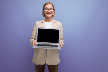 successful 50s middle aged woman in jacket with laptop to work on studio background with copy space