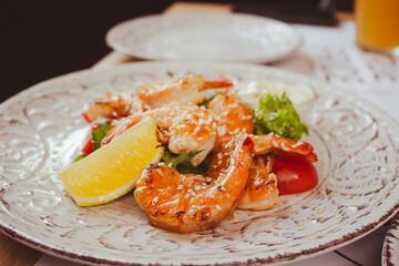 Shrimps with lemon and salad. Seafood close up. Served fish dish. Fish restaurant menu. Fried prawns with lemon. Mediterranean mollusk plate. Flat lay photo. 