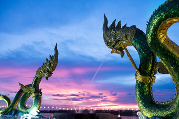 Big green naga statue in riverside on mekong river is landmark in nongkhai city Thailand with twilight background. - obrazy, fototapety, plakaty