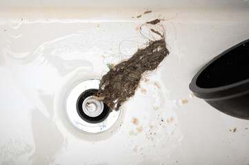 Removing blockage using drain cleaner. Old hair bunch caused sink drainage blockage - 629501353