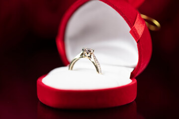 Romantic day concept. Engagement ring lying on shining table on the red roses background. 