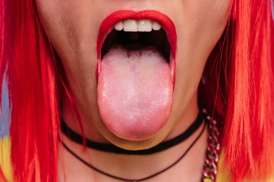 A wide open mouth with a young girl's tongue sticking out. Beautiful face close-up.