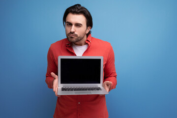 charming positive 30s man in red shirt showing laptop screen mockup