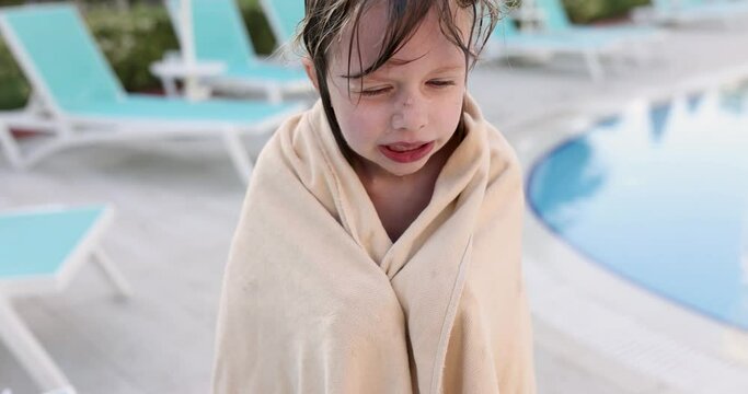 Frozen little girl in towel after swimming in pool. Hypothermia in children concept
