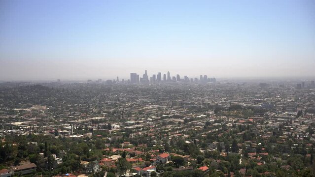 Panning down view of the LA skyline from the Griffith Observatory with blue sky and lots of houses and neighborhoods.