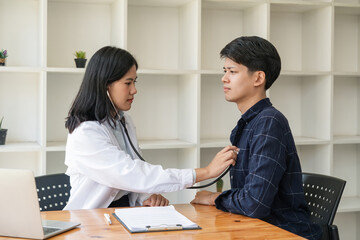 Asian man patient are checked up his health while a woman doctor use a stethoscope to hear heart...