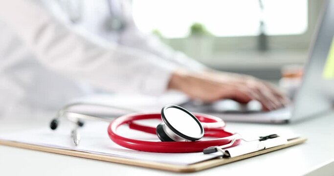 Red stethoscope background typing doctor on laptop. Medical education concept