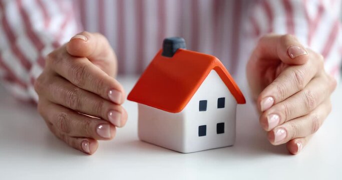 Insurance agent protects house with hands. Home insurance protection concept