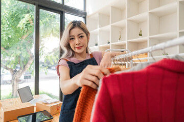 Asian beautiful woman entrepreneur of online sell clothing with laptop and notebook on desk in home office