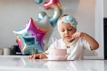 Adorable three year old kid celebrating his birthday and blowing candles on homemade baked cake,...