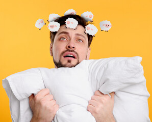 Exhausted man with pillow suffering from insomnia on yellow background. Illustrations of sheep...