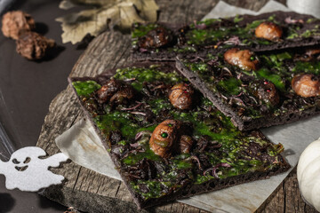 Halloween concept food. Flatbread or pizza with squid Ink, green cheese, mushrooms and purple onion