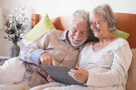 Portrait Of Happy Senior Couple Together In Bed, Two Elderly People Relaxing At Home Using Digital Tablet Technology, Leisure Time