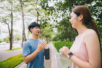 young Asian couple staying hydrated after running jogging. Healthy lifestyle concept.